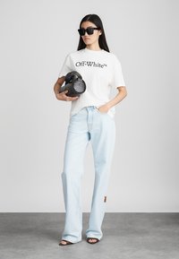 Valge lühikeste varrukatega T-särk koos "Off-White" logoga, helesinised laiad teksad, must ovaalne klamberkott ja tume ülemõõdus päikeseprillid.