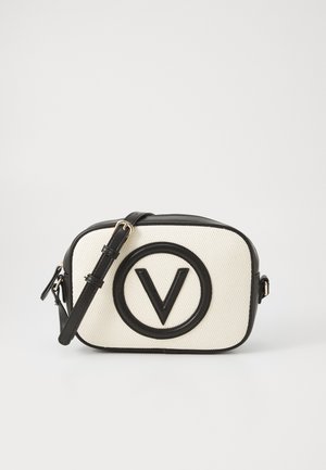 Kompakt hvid og sort skuldertaske med justerbar rem og et stort sort rundt emblem med et "V" på fronten.