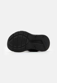 Svart sneaker sula med texturerat greppmönster, med djärva spår och logotyp. Materialet verkar vara gummi med en robust design.
