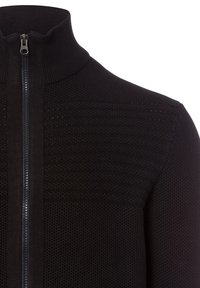Schwarzer Reißverschluss-Pullover mit hohem Kragen, strukturiertem Strickmuster und glattem Stoff rund um den Reißverschluss.