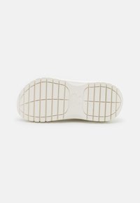 White rubber outsole with a textured, patterned tread design. Features horizontal and vertical grooves for traction and stability.