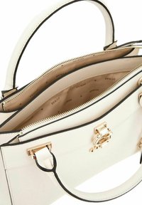 Borsa sintetica bianca con finiture nere, dotata di manico superiore, hardware dorato, chiusura con zip e un interno beige a fantasia.
