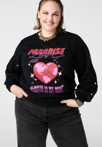 Zwarte sweatshirt met een kleurrijke afbeelding van een hart en aarde, inclusief tekst. Lange mouwen met subtiele pofdetails bij de manchetten. Zachte stof.