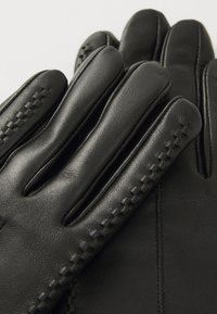 Gants en cuir noir avec une texture lisse, dotés de quatre doigts allongés et de coutures décoratives sur le côté.