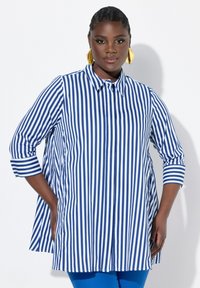 Camicia a righe blu e bianche con colletto, maniche a tre quarti e una silhouette leggermente svasata. Tessuto morbido.