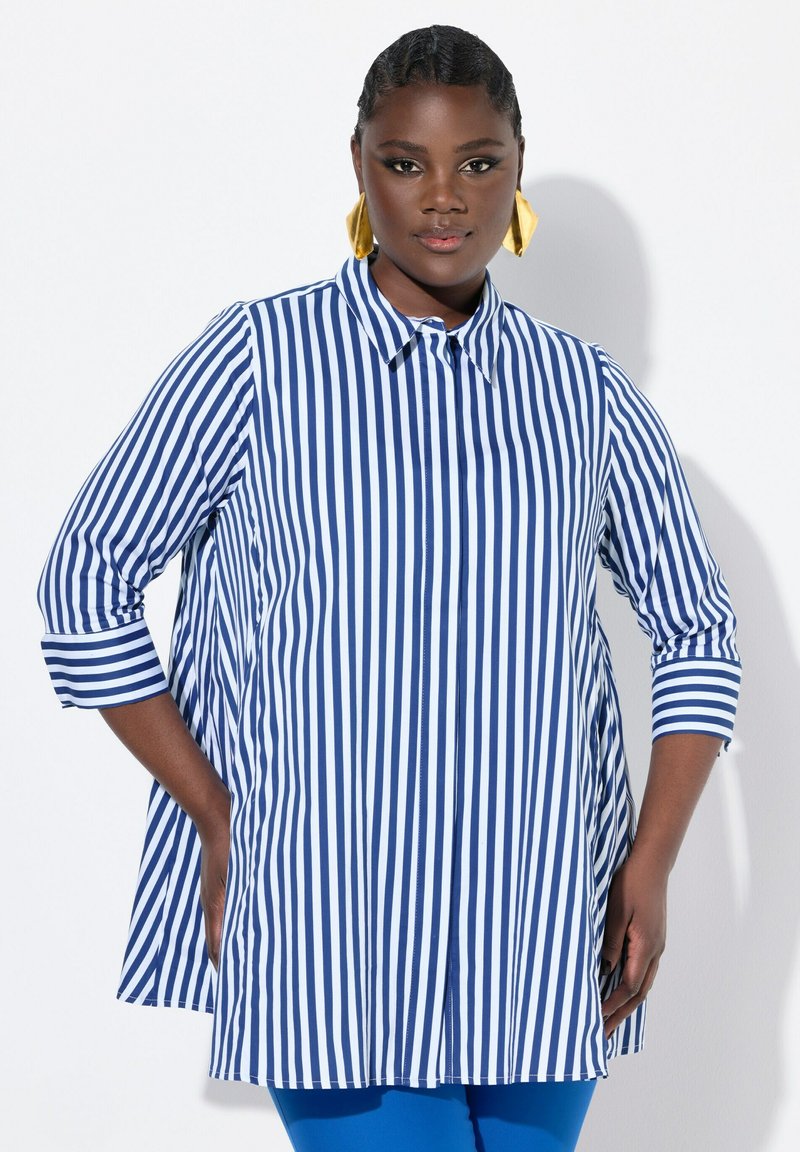 Camicia a righe blu e bianche con colletto, maniche a tre quarti e una silhouette leggermente svasata. Tessuto morbido.