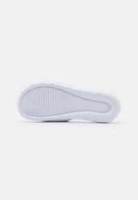 Hvit sneakersåle med et strukturert, rippet mønster og en fremtredende Nike-logo. Glatt design med avrundede kanter og ingen synlige akcenter eller merker.