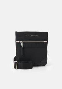 Borsa a pochette nera in nylon con chiusura a zip, dotata di tasca frontale, tracolla regolabile e logo del brand sulla parte superiore.