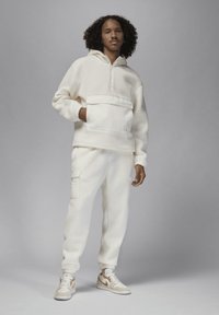 Hvid fleece-pullover med halvlynlås og forlommer, parret med matchende fleece-bukser. Fodtøj med creme- og beige farveskema.