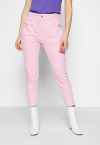 Rosa bomullsjian med smal passform, hög midja, framfickor och silverdetaljer. Matchas med vita ankelstövlar.