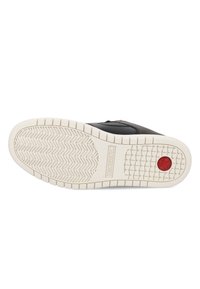 Black sneaker with textured upper and white rubber sole, featuring a red accent on the heel and a zigzag tread pattern.