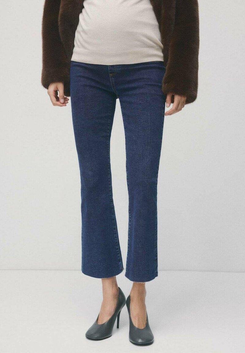 Marineblauwe jeans met wijde pijpen in denim met een gladde textuur. Gecombineerd met zwarte hoge hakken met een puntige neus.