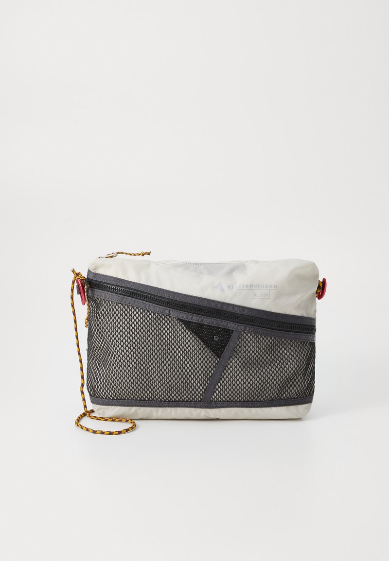 Grijze en zwarte crossbodytas met een mesh voorkant, ritszakken en een kleurrijke gevlochten strap. Voorzien van een geometrisch ontwerp en duurzaam materiaal.