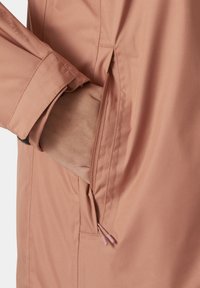 Chaqueta rosa claro con un bolsillo con cremallera en la cadera. Textura suave con un acabado ligeramente brillante y tiradores de contraste.
