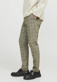 Licht olijfgroene geblokte broek met een slim fit, voorzien van een ruitpatroon en voorzakken, gecombineerd met zwarte veterschoenen.