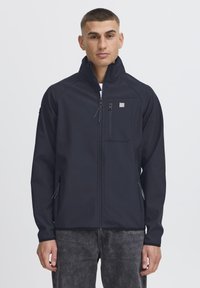 Hajózási softshell dzseki magas gallérral, cipzáros zsebekkel és letisztult dizájnnal. Elöl található egy zseb, textúrált anyagú kivitel.