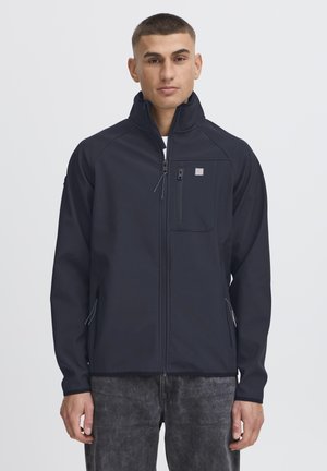Marineblå softshell-jakke med høj krave, lynlåslommer og slankt design. Har en frontlomme og struktureret stoffinish.