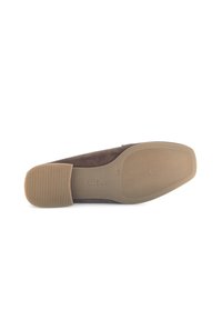 Bruine suède platte schoen gezien vanuit de zool, met tekstuur gripgebieden en maat 4½ gemarkeerd op de tan rubberen zool.