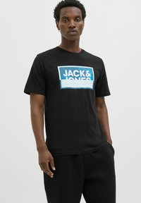 Zwart katoenen T-shirt met een rechthoekige blauwe grafiek en de tekst "JACK&JONES". Korte mouwen, ronde hals en een ontspannen fit.