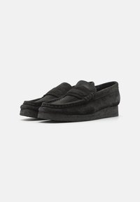 Sorte fløyelsloafers med rund tå og hevet sømdetalj. Strukturerte såler gir godt grep. Slip-on design og lav høyde.