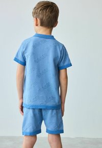 Blauwe katoenen set met korte mouwen, met een getextureerd, herhaald logo-patroon. Inclusief een overhemd met kraag en bijpassende shorts met omslagranden.