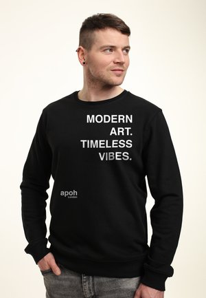 Sort sweatshirt med hvid tekst "MODERN ART. TIMELESS VIBES." på fronten. Har rund halsudskæring og ribbede manchetter. Brandlogo nederst til venstre.