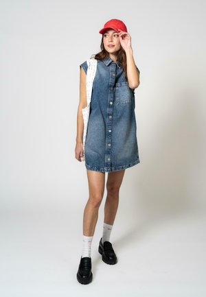Denim ærmeløs kjole med frontlomme, lys til mørk blå ombre. Sammen med en rød kasket, sorte platform sko og hvide ankelstrømper.