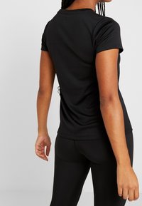 Black short-sleeve t-shirt with a round neck, fitted design, smooth texture, and minimalistic style, showing the back view.