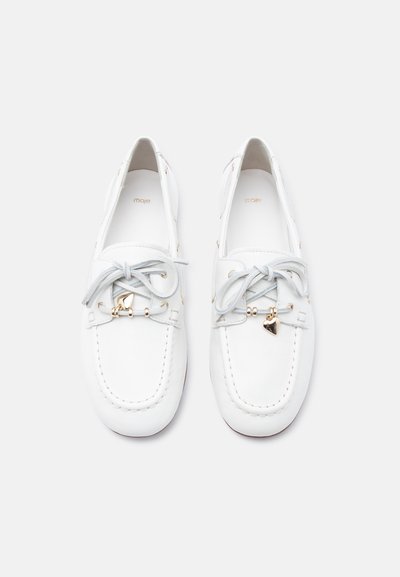 Paire de mocassins blancs en cuir avec lacets gris et petits pendentifs en forme de cœur dorés sur fond blanc.