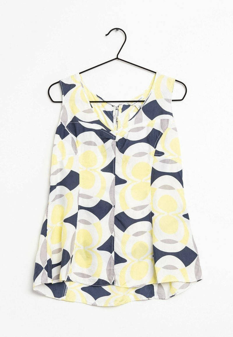 Blouse sans manches col en V sur cintre noir avec motifs circulaires abstraits en jaune, bleu marine, gris et blanc sur tissu léger.