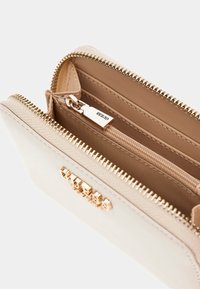 Portafoglio color crema in pelle con chiusura a zip, dotato di accessori dorati e un ampio interno con slot per carte e un compartimento con zip.