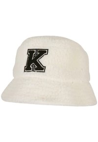 Pălărie albă, pufoasă, făcută dintr-un material texturat, cu litera „K” brodată în negru pe partea din față. Design cu bor plat și coroană rotundă.