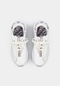 Chaussures de sport blanches avec une tige en mesh respirant, des lacets gris clair et une semelle intérieure à motifs. Semelle texturée pour une adhérence et un soutien.