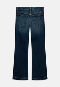 Vaqueros de mezclilla azul oscuro con un diseño de pierna acampanada. Presentan dos bolsillos traseros con costuras sutiles y un dobladillo limpio en el tobillo.