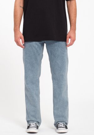 Light blue denim jeans with a straight fit, featuring a faded texture. Paired with a black t-shirt and black sneakers.