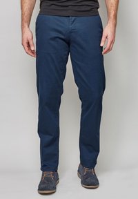 Pantalones de mezclilla de algodón en color marino con corte recto, que presentan una textura suave y un diseño minimalista, combinados con zapatos de ante grises.