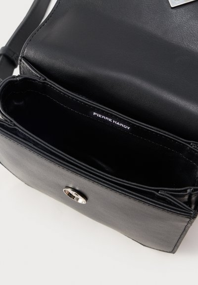 Μαύρη δερμάτινη τσάντα ώμου με ανοιχτό καπάκι, ασημένιο μαγνητικό κούμπωμα και ετικέτα "Pierre Hardy" στο εσωτερικό.