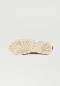 Beige kummist kinga välistald, millel on kalasabamuster, koos brändinime "GUESS" reljeefse logoga. Sile, hästi määratletud haardunurgad.