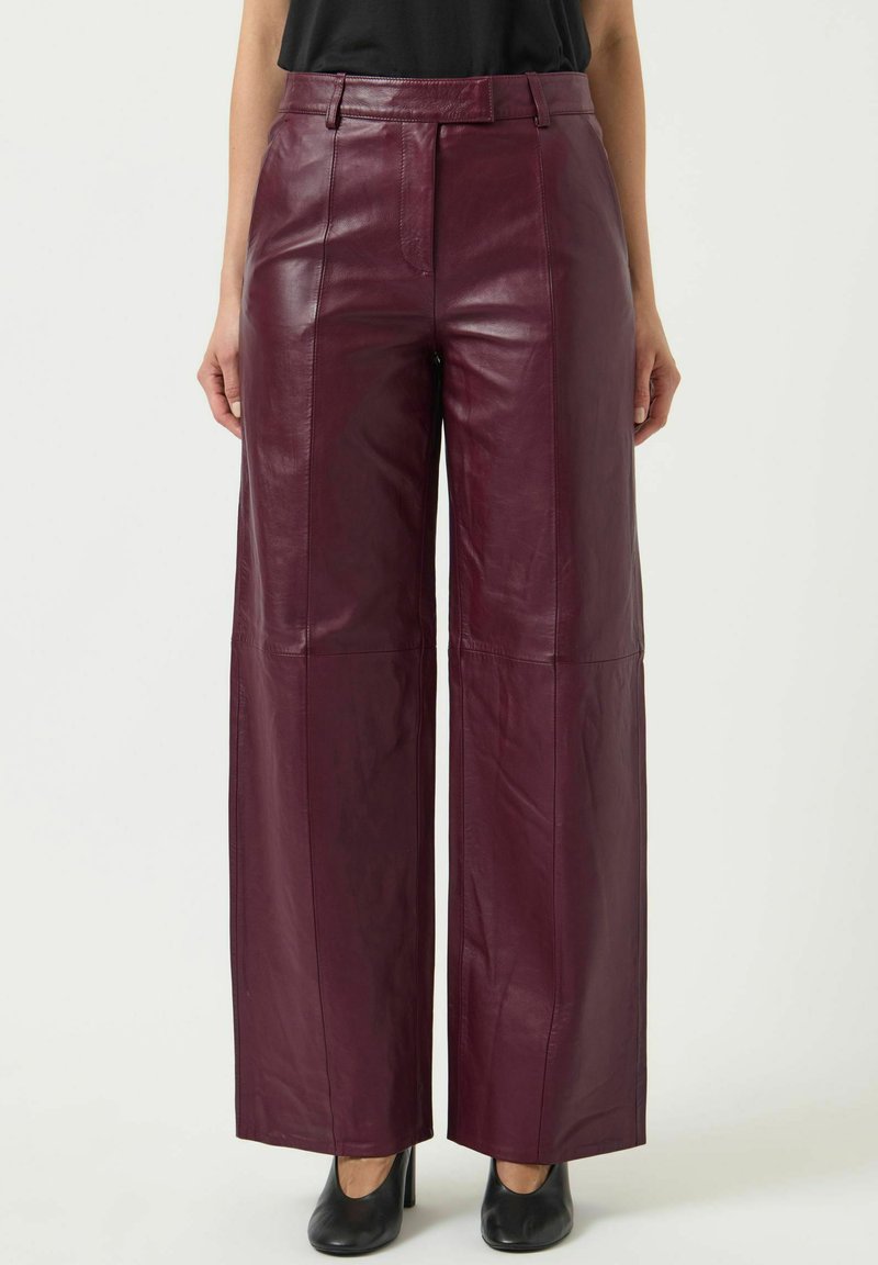 Bordeaux leren wijde broek met een hoge taille, voorzien van een gladde textuur en gestikte paneeldetails. Draag met zwarte hoge hakken.