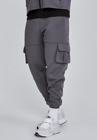 Grå cargo byxor med flera fickor, avsmalnande design och ribbade muddar. Tillverkade av mjukt, stretchigt material för komfort.