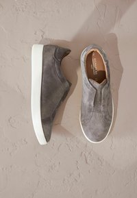 Gray suede slip-on sneakers featuring a white rubber sole, smooth texture, and subtle stitching details on the upper.