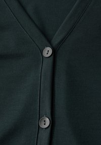 Ciemnozielony kardigan z dekoltem w serek, z zapięciem na guziki i gładką fakturą. Guziki są okrągłe i mają po dwa otwory.