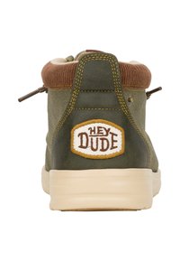 Zapatilla alta verde con cuello marrón, suela beige y logotipo bordado "HEY DUDE" en un óvalo amarillo en el talón. Tela texturizada.
