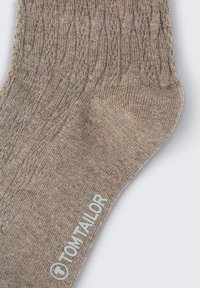 Braune Stricksocken mit geripptem Muster, mit verstärkter Zehen- und Fersenpartie. Logo auf der Seite gedruckt. Weiches, mitteldickes Material.