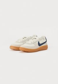 Lichtbeige sneakers met een marineblauwe swoosh, voorzien van textiel, ronde neusontwerp en een gumrubberen zool. Vetersluiting.