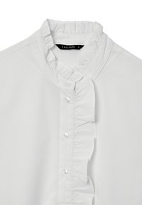 Camicia bianca con colletto e patta arricciati. Realizzata in tessuto liscio, presenta bottoni lucidi e un design aderente. Etichetta del marchio visibile.