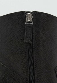 Schwarzer Lederstiefel mit strukturiertem Finish, ausgestattet mit einem silbernen Reißverschluss und einer glatten, schrägen Nahtdetails im oberen Bereich.