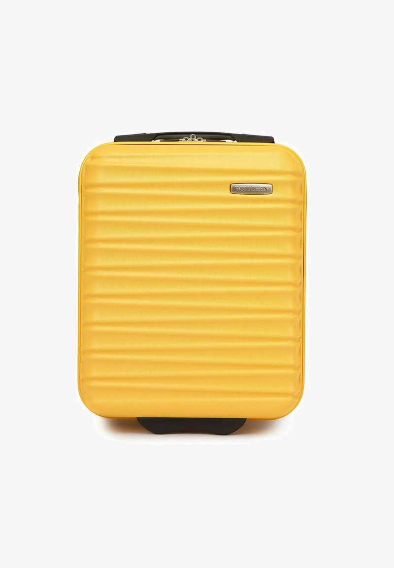 Gele harde koffer met een geribbelde textuur, ritssluiting, zwarte accenten en een opvallend logo aan de voorkant. Compacte en rechthoekige vorm.