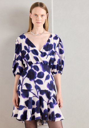 Une robe portefeuille à manches courtes en tissu blanc, ornée d'un imprimé floral bleu et violet, avec une taille froncée et une jupe évasée.