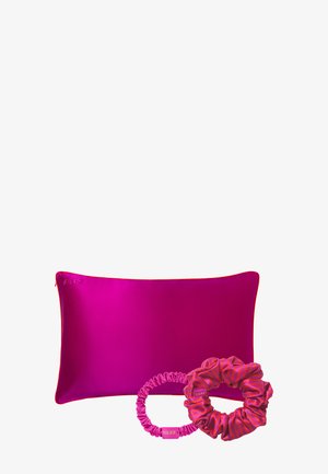 Bright pink silk rectangular pillow with two matching pink silk hair scrunchies, one solid and one striped, on a white background.